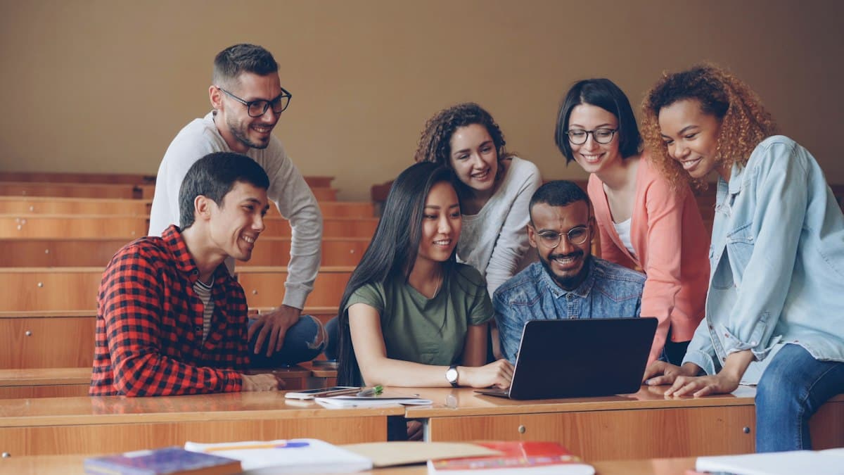 Estudantes colaborando e sorrindo em volta de um notebook